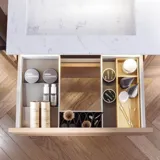 Bathroom inspiration with washbasin cabinets and wall cabinets in light oak with grooves, elegant double sink, beautiful mirror cabinet with light, herringbone floor in light wood, and white marble wall give a classic, bright, and sleek look.