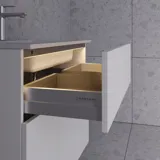 Stylish and spacious bathroom inspiration with a large round mirror with a black frame, dark stone sink, colored toilet, upper cabinet, and open shelf in a sophisticated and muted design