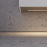 Minimalist and sleek bathroom inspiration with vanity unit, base cabinets, and tall cabinets in golden oak, large round mirror with light control, colored toilet, and countertop sink