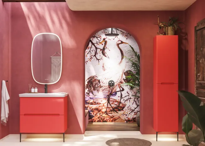 Bathroom inspiration with red walls, softly shaped red vanity and tall cabinet, elegant white sink and beautiful oval mirror with light, creating a vintage look together with the natural surroundings