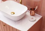 Large vintage retro bathroom inspiration with a terracotta-colored grooved vanity, elegant thin countertop with a beautiful vessel sink, stylish oval mirror with brass edge. Pink tiles and grey herringbone tiles give a romantic and feminine look