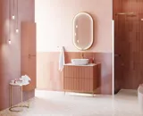 Large vintage retro bathroom inspiration with a terracotta-colored grooved vanity, elegant thin countertop with a beautiful vessel sink, stylish oval mirror with brass edge. Pink tiles and grey herringbone tiles give a romantic and feminine look