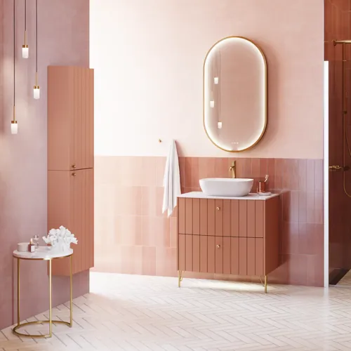 Large vintage retro bathroom inspiration with a terracotta-colored grooved vanity, elegant thin countertop with a beautiful vessel sink, stylish oval mirror with brass edge. Pink tiles and grey herringbone tiles give a romantic and feminine look