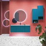 Large bathroom inspiration with blue special color grooved furniture, thin elegant sink, and beautiful round mirrors, red walls, and terrazzo floor create a strong contrast to the furniture, giving a stylish and urban look.