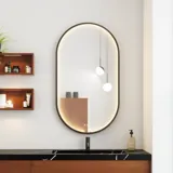 Modern and stylish bathroom inspiration with an oval mirror with a black frame and light control, colored toilet, vanity unit, base cabinets, and cabinets in reddish-brown oak, Silestone sink and matching floor