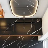 Modern and stylish bathroom inspiration with an oval mirror with a black frame and light control, colored toilet, vanity unit, base cabinets, and cabinets in reddish-brown oak, Silestone sink and matching floor