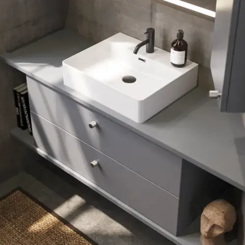 Bathroom inspiration with sloped walls inspiration, grey vanity unit and upper cabinet, custom-made countertops, modern square countertop basin, square mirror with lights, raw concrete walls and floors create an urban look