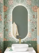 Bathroom inspiration with green special color bathroom furniture with natural oak sides, elegant grooves, stylish countertop with romantic oval countertop sink, beautiful oval mirror, combined with floral wallpaper gives a graceful, vintage retro look.
