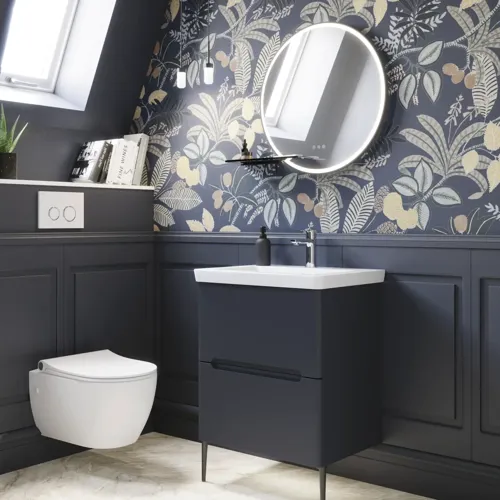 Bathroom inspiration with dark blue wall panels, romantic floral wallpaper, dark blue vanity with soft curves, and a beautiful round mirror with light, creating a vintage look