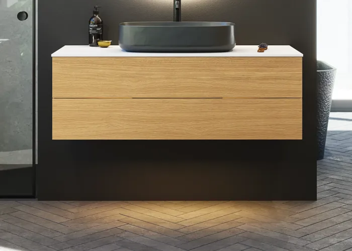 Minimalist and sleek bathroom inspiration with vanity unit, base cabinets, and tall cabinets in golden oak, large round mirror with light control, colored toilet, and countertop sink