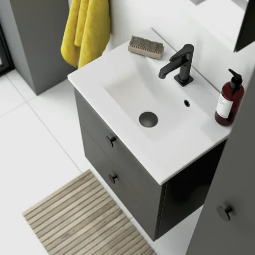 Large bathroom with slanted ceiling inspiration featuring grey bathroom furniture with black, round handles, elegant sink, and beautiful small mirror cabinet with light. Large white tiles and grey wall provide a modern and minimalist look.