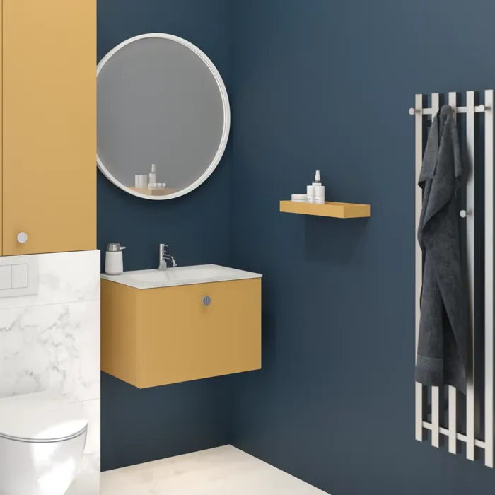 Small bathroom with dark blue walls and soft yellow tones, round mirror, and elegant towel rail.
