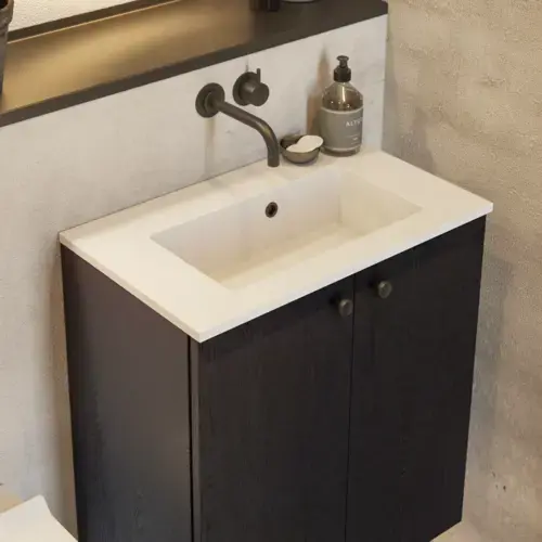 Bathroom inspiration with a black oak washbasin cabinet, an elegant round mirror and sink, stylish accessories, cactus plants, and walls in raw materials give a rough, industrial, and urban look.