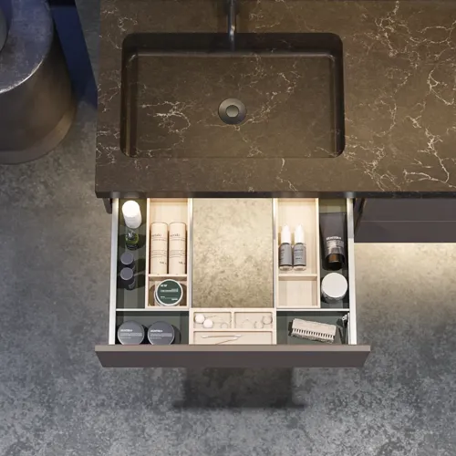 Stylish and spacious bathroom inspiration with a large round mirror with a black frame, dark stone sink, colored toilet, upper cabinet, and open shelf in a sophisticated and muted design.