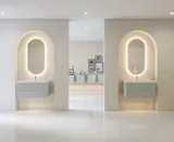 Stylish and modern bathroom inspiration with oval mirrors with light control, stone sinks, and vanity units with fine and elegant grooves in a minimalist design, the bathroom has a light and airy atmosphere with elegant lighting and refined details.