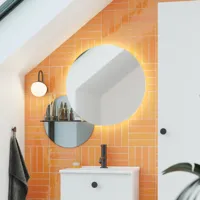 Bathroom with sloping ceiling inspiration with small white vanity unit and tall cabinet with round black handles, as well as beautiful round mirror, orange tiles give a fresh and modern look.