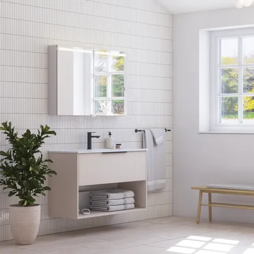Large bathroom inspiration with small oblong tiles, elegant vanity unit and tall cabinet in light beige with beautiful narrow stripes, black modern elongated handles and stylish mirror cabinet with light to create a romantic atmosphere.
