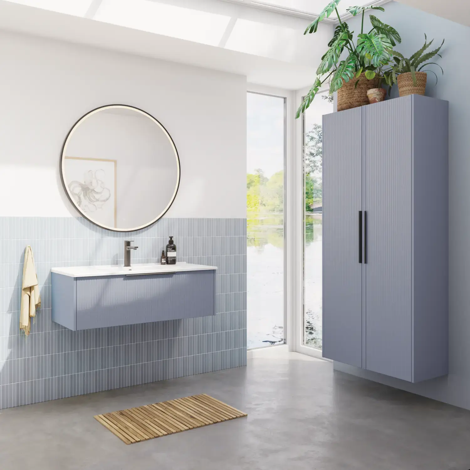 Bathroom inspiration with elongated light blue tiles and concrete floor, elegant light blue vanity unit with beautiful narrow stripes, sleek and thin sink, double tall cabinet with narrow stripes, and a minimalist round mirror with a black edge and light.