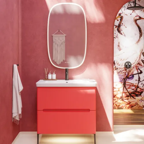 Bathroom inspiration with red walls, softly shaped red vanity and tall cabinet, elegant white sink and beautiful oval mirror with light, creating a vintage look together with the natural surroundings